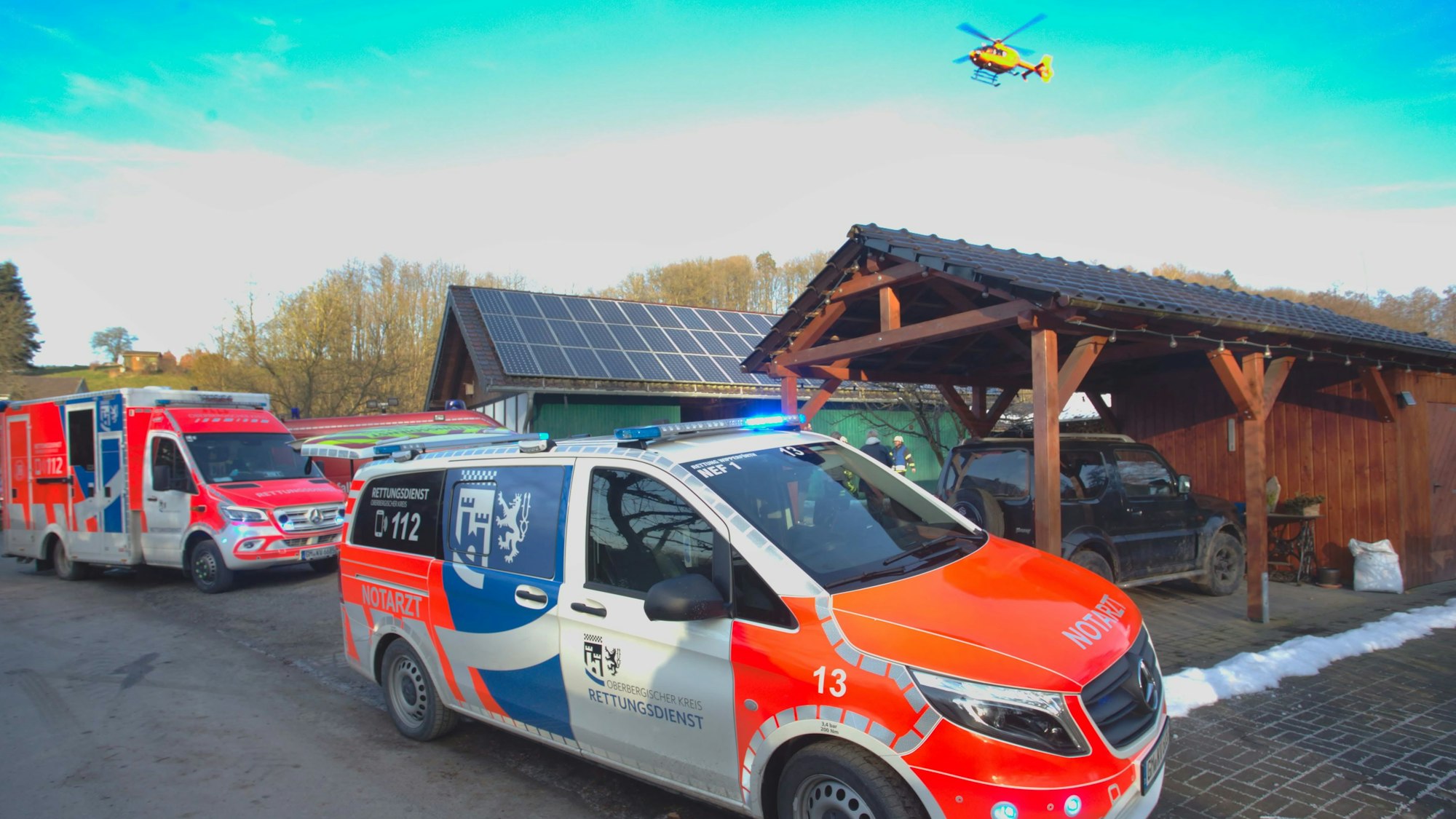 Rettungsfahrzeuge stehen am Boden, in der Luft kreist ein Hubschrauber.
