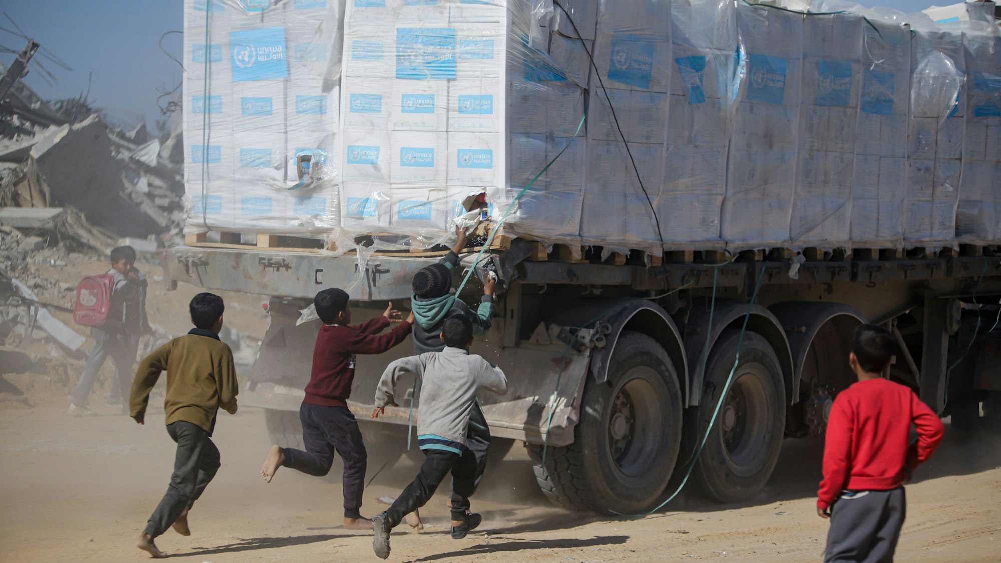 Rafah: Palästinenser rennen einem Lastwagen mit humanitären Hilfsgütern nach, der über den Kerem-Shalom-Übergang von Ägypten in den Gazastreifen eingefahren ist, nachdem ein Abkommen über eine Waffenruhe zwischen Israel und der Hamas in Kraft getreten ist.