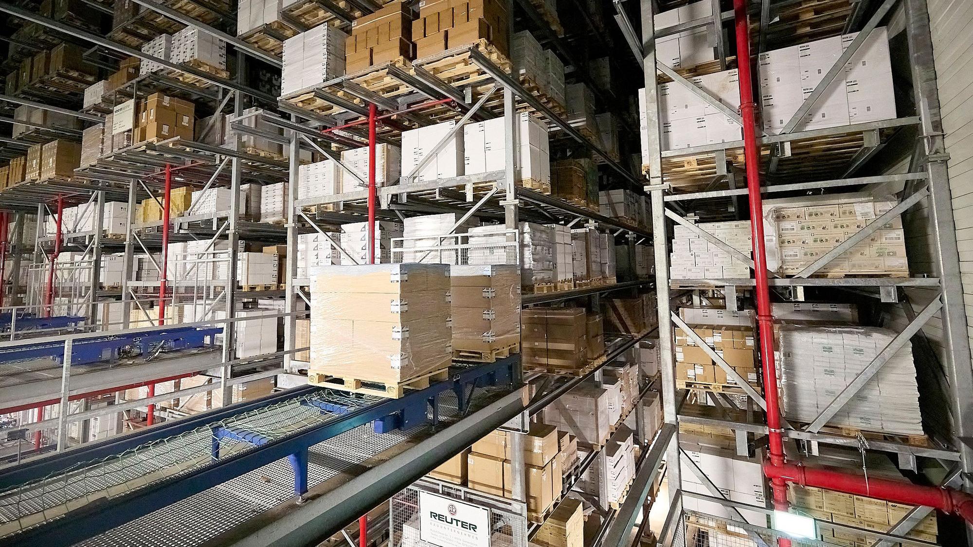 Im Hochregallager des Logistikzentrums von Papstar in Kall werden Pakete auf Paletten vollautomatisch durch eine Halle gefahren.