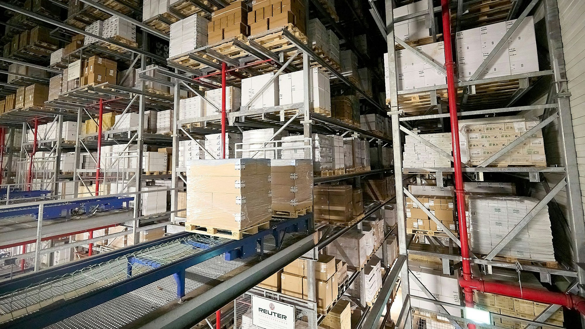 Im Hochregallager des Logistikzentrums von Papstar in Kall werden Pakete auf Paletten vollautomatisch durch eine Halle gefahren.
