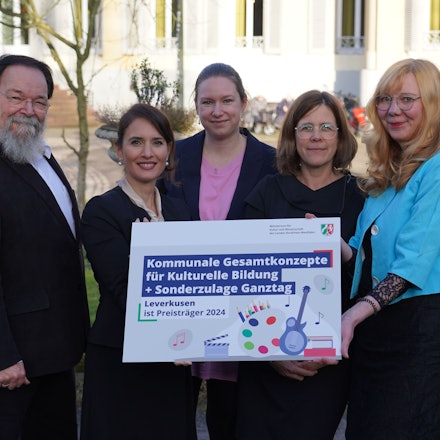 Bürgermeister Bernhard Marewski, Staatssekretärin Ministerium Kultur und Wissenschaft NRW Gonca Türkeli-Dehnert mit Katharina Baarhs, Mirjam Wandhoff und Anke Holgersson vom kommunalen Bildungsbüro Leverkusen halten die Auszeichnung für Kulturelle Bildung in der Hand