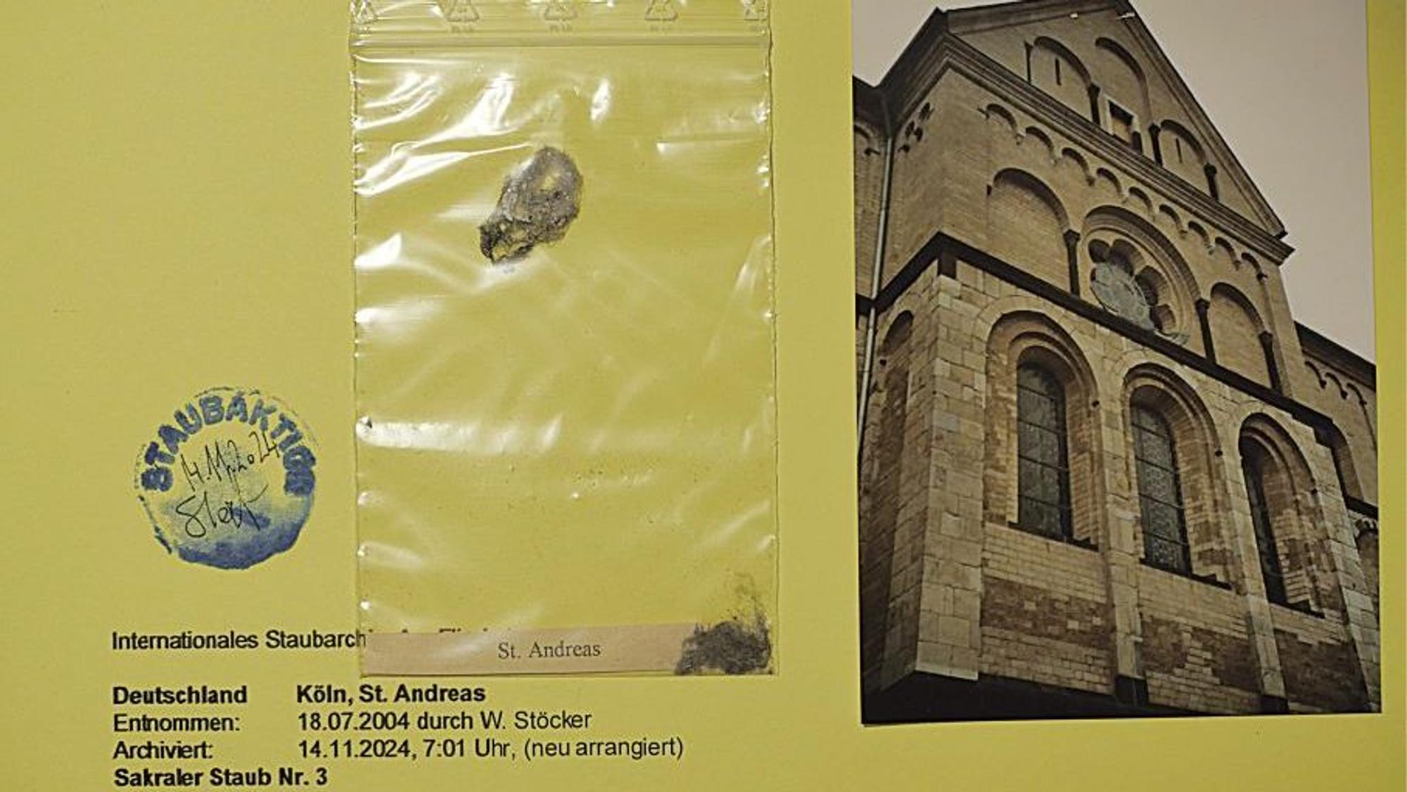 Eine eingetütete Probe aus dem Staub-Archiv von Wolfgang Stöcker. Daneben liegt eine Fotografie von der Kölner Kirche St. Andreas.