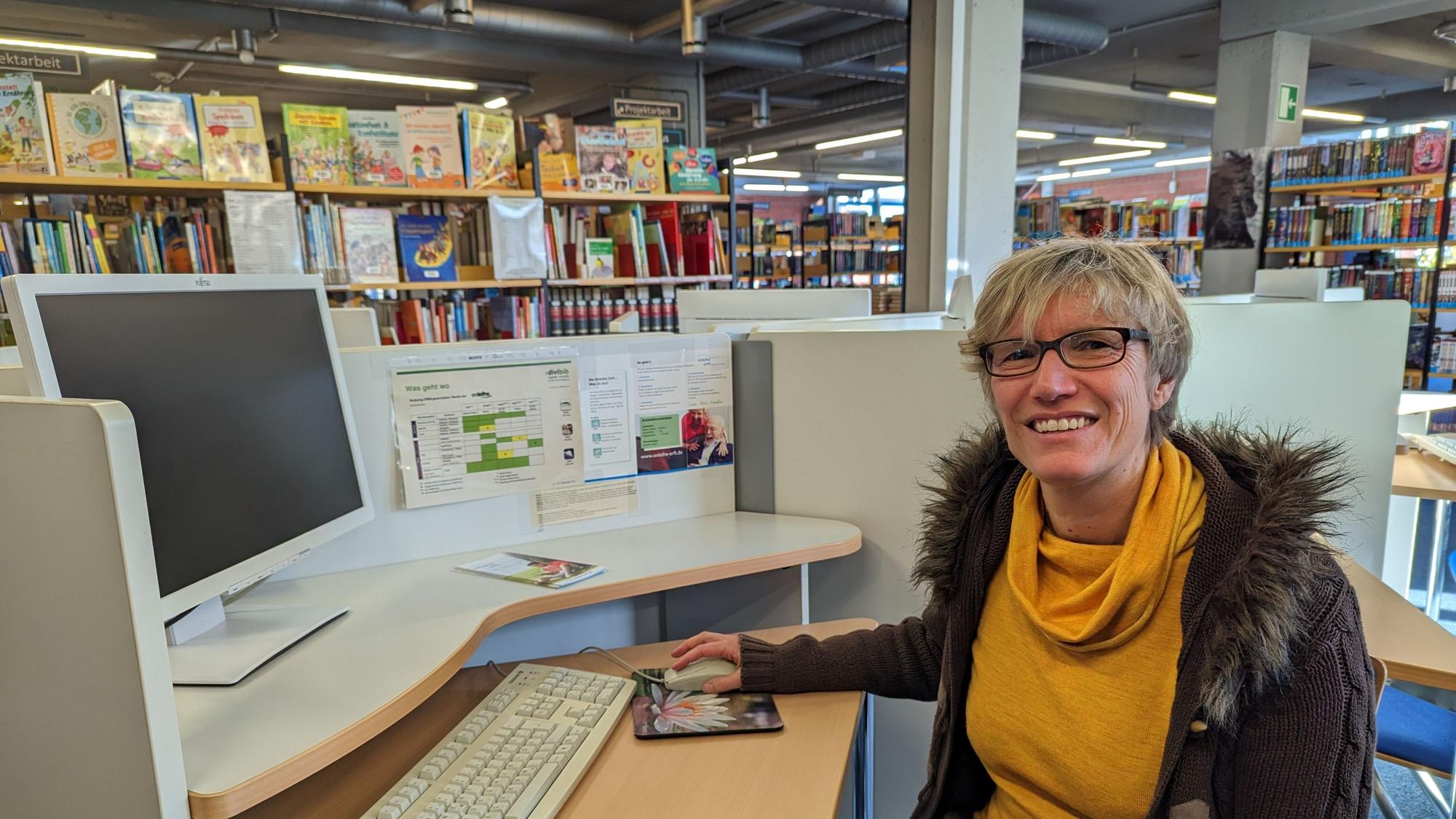 Das Foto zeigt die Büchereileiterin an einem Computerarbeitsplatz, im Hintergrund die alten Bücherregale.