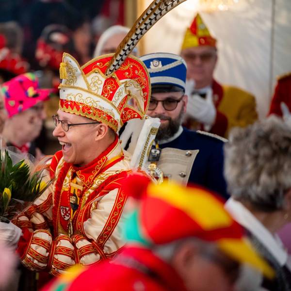 Karnevalsprinz Jens Pesch verteilt in einem Saal voller Senioren Tulpensträuße.