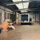 .Foto der Lagerhalle, in der unter anderem ein offener Transporter steht.