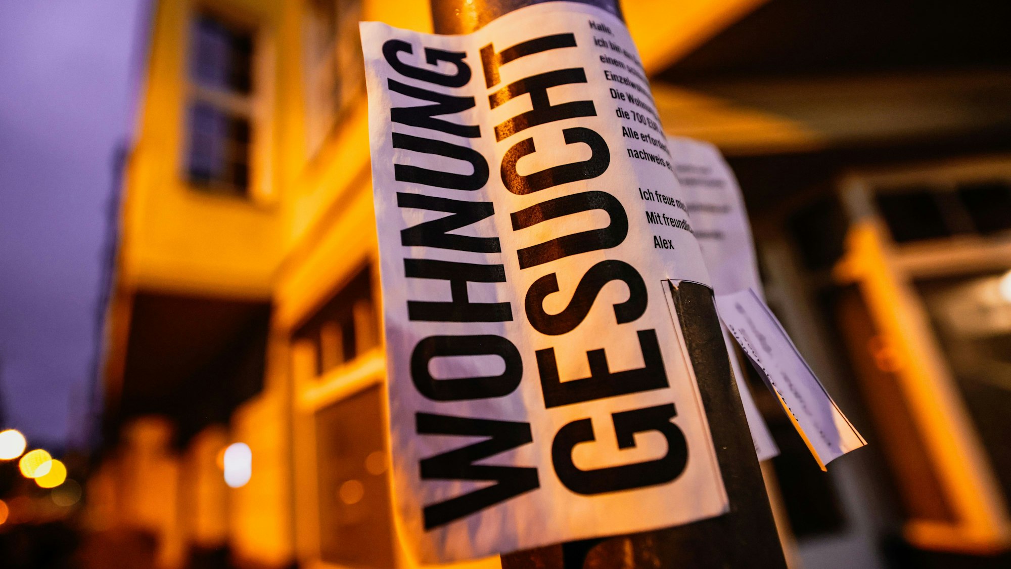 Ein Zettel mit der Aufschrift «Wohnung gesucht» hängt vor Wohnhäusern in Köln