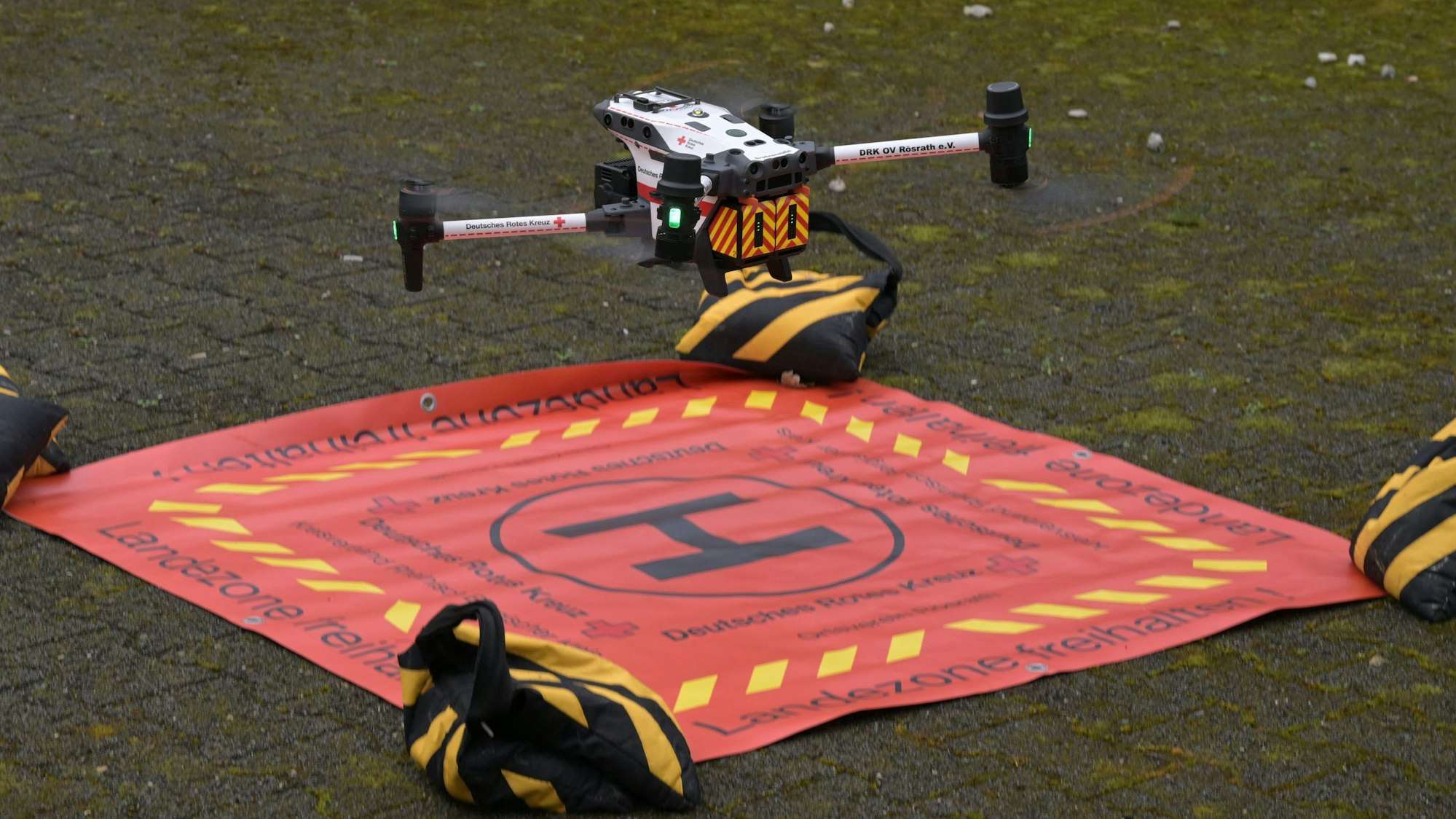 Eine Drohne hebt von einem Landeplatztuch ab.