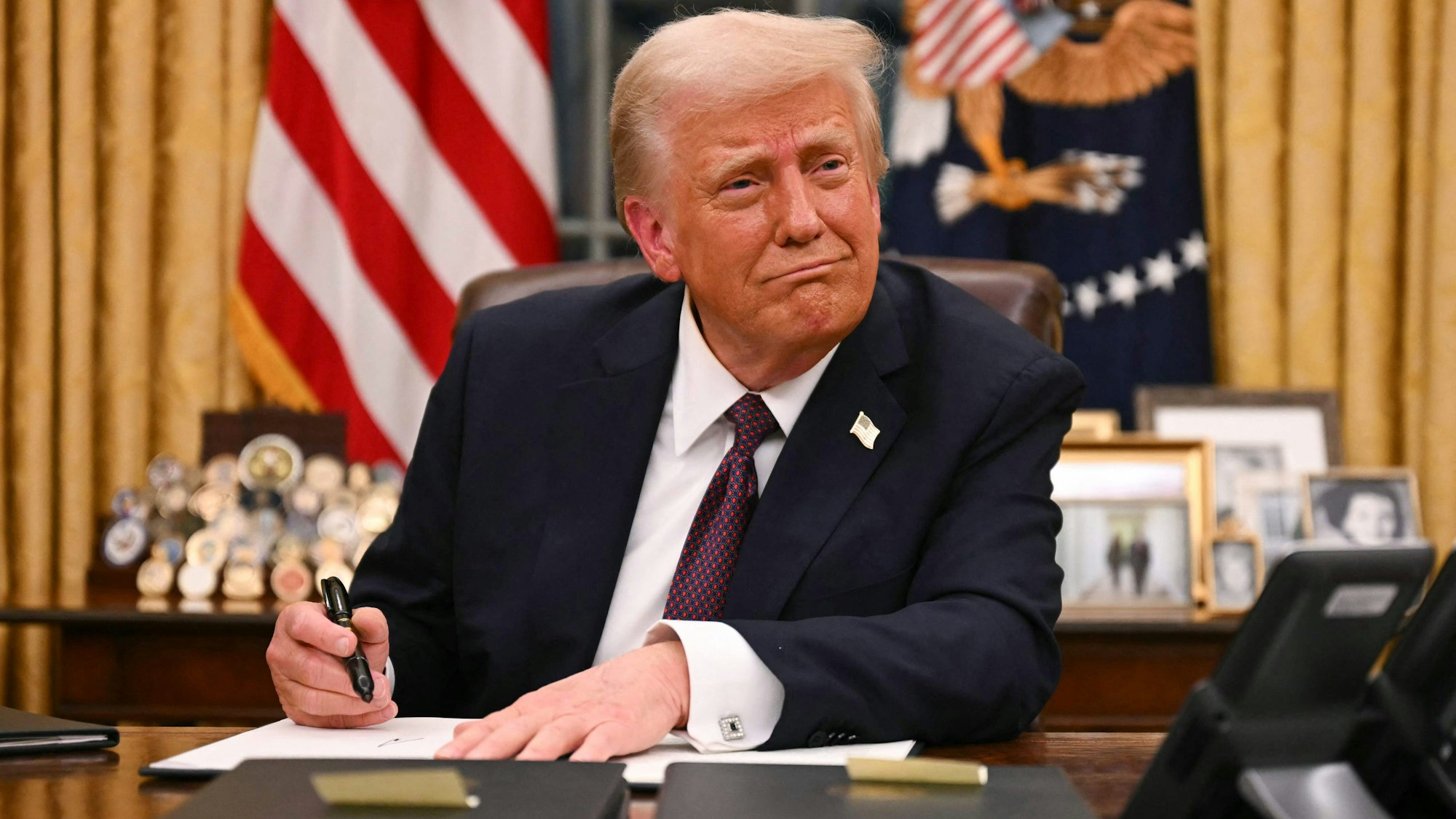 Donald Trump unterzeichnet am Schreibtisch ein Dekret.