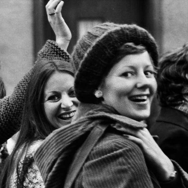 Vier Frauen winken lachend in die Kamera.