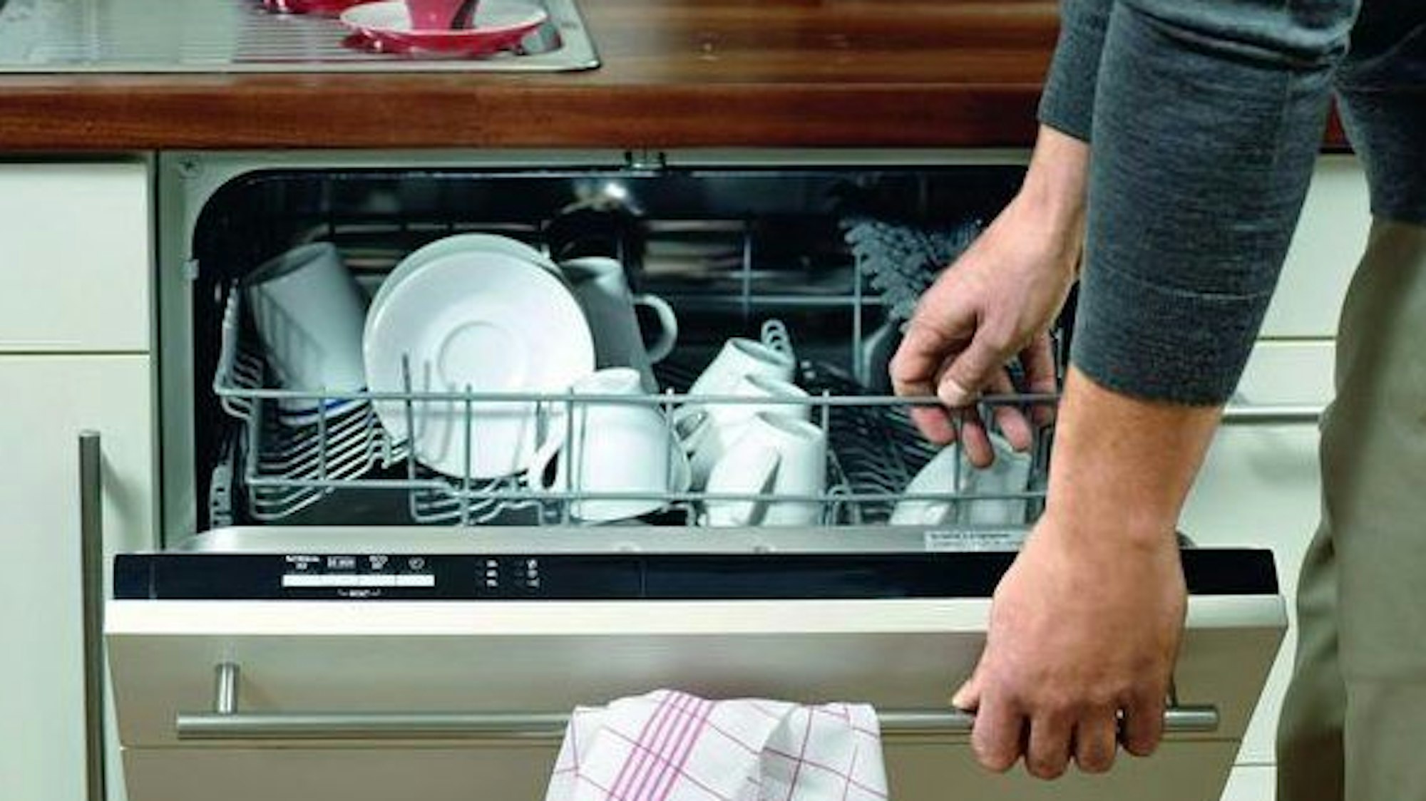 Ein Mann öffnet einen Geschirrspüler.