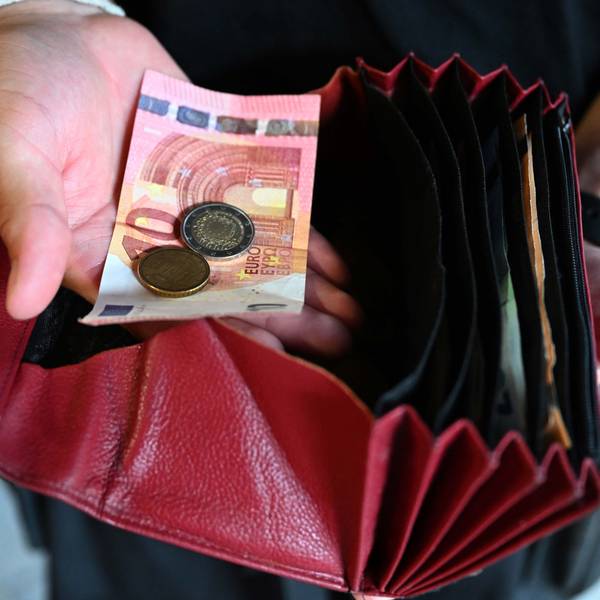 Ein Kellner eines Restaurants hält einen Geldbeutel in der Hand, während er in der anderen Hand Geld hält.