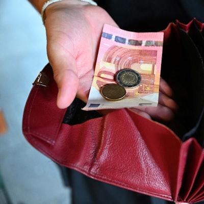 Ein Kellner eines Restaurants hält einen Geldbeutel in der Hand, während er in der anderen Hand Geld hält.