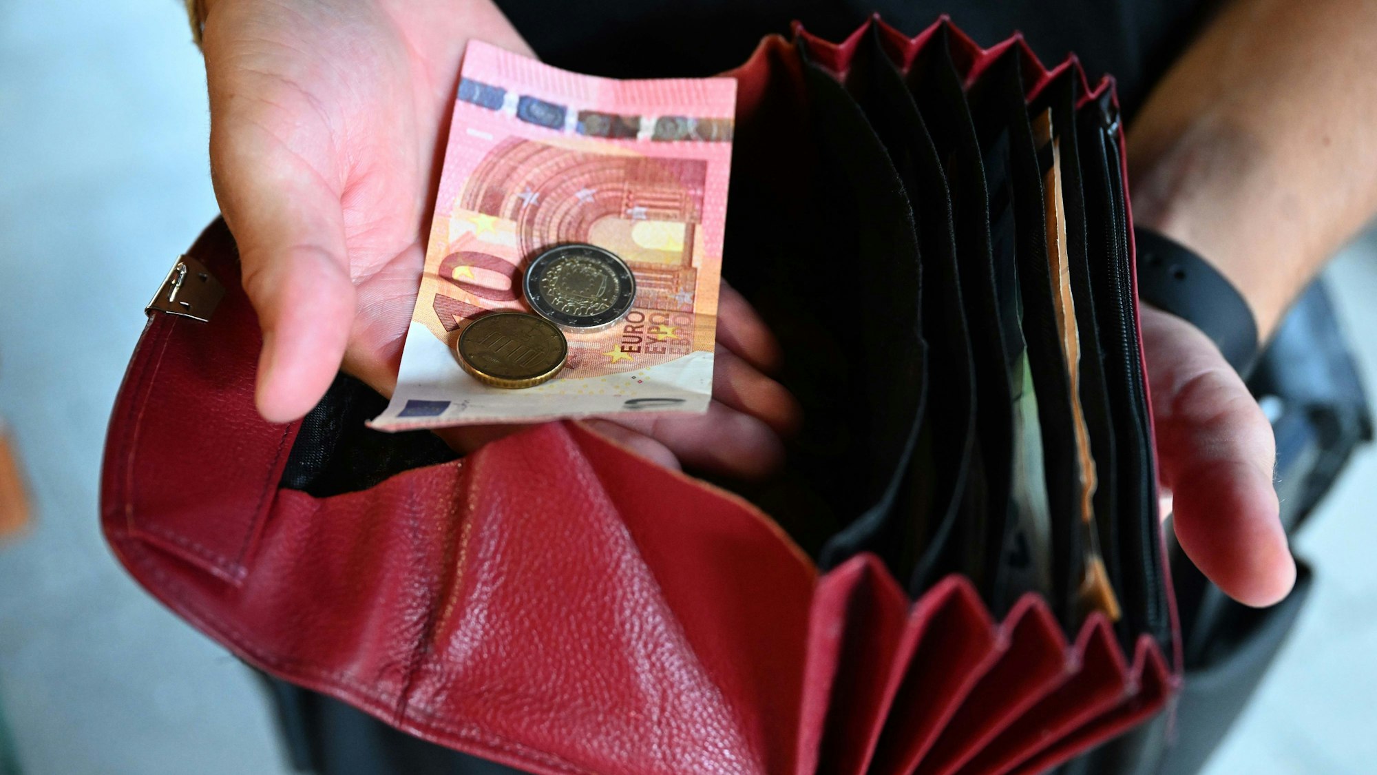 Ein Kellner eines Restaurants hält einen Geldbeutel in der Hand, während er in der anderen Hand Geld hält.