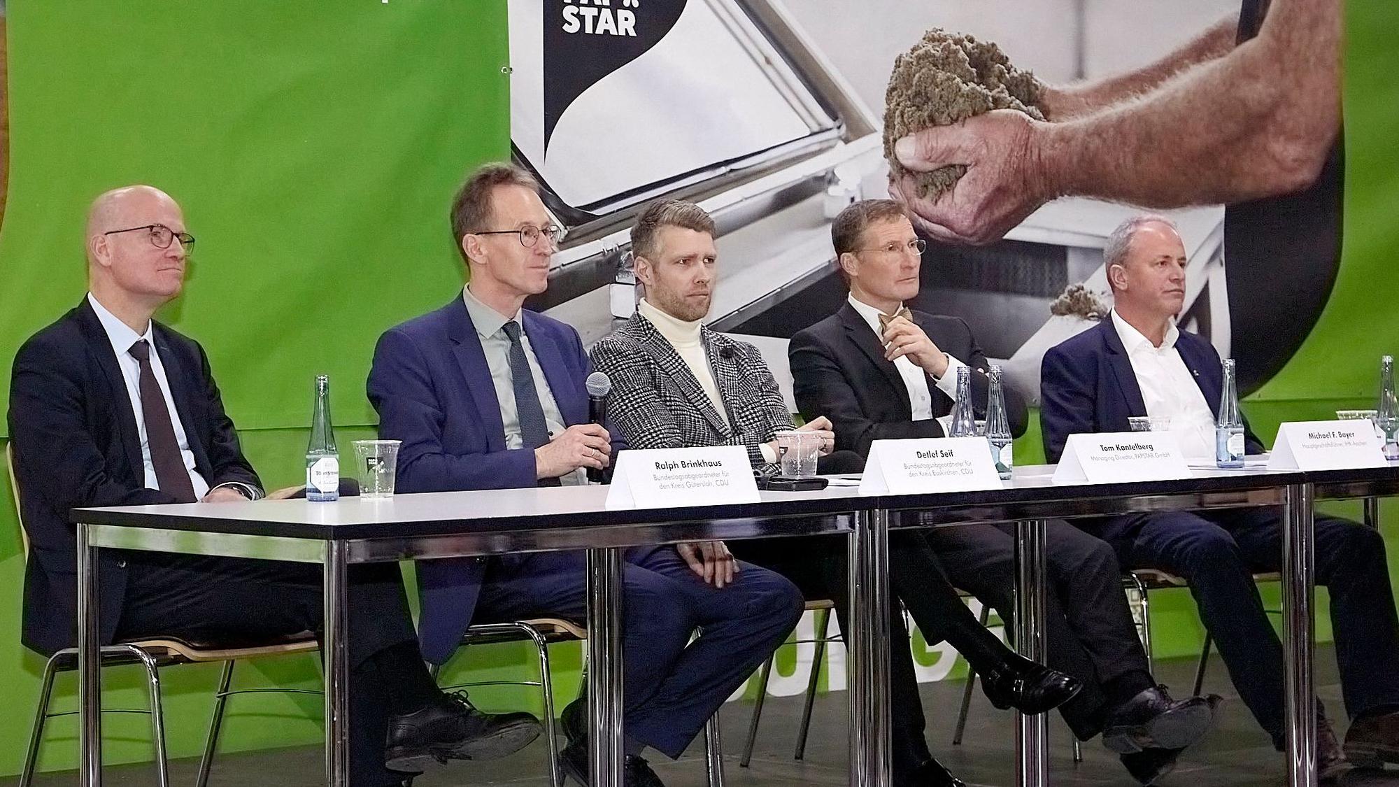 Fünf Männer sitzen bei einer Podiumsdiskussion in der Kaller Firma Papstar an einem Tisch.