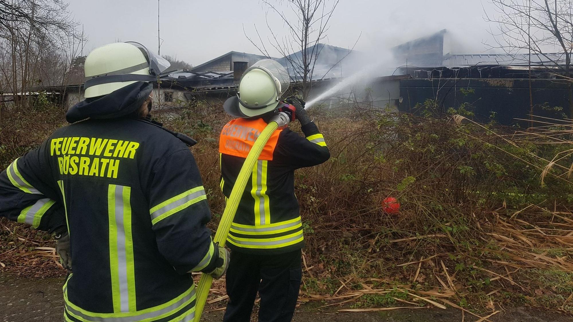 Zwei Feuerwehrmänner löschen mit einem C-Rohr.