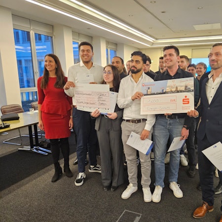 Viele Menschen halten „Preisgeld-Checks“ in den Händen und freuen sich.