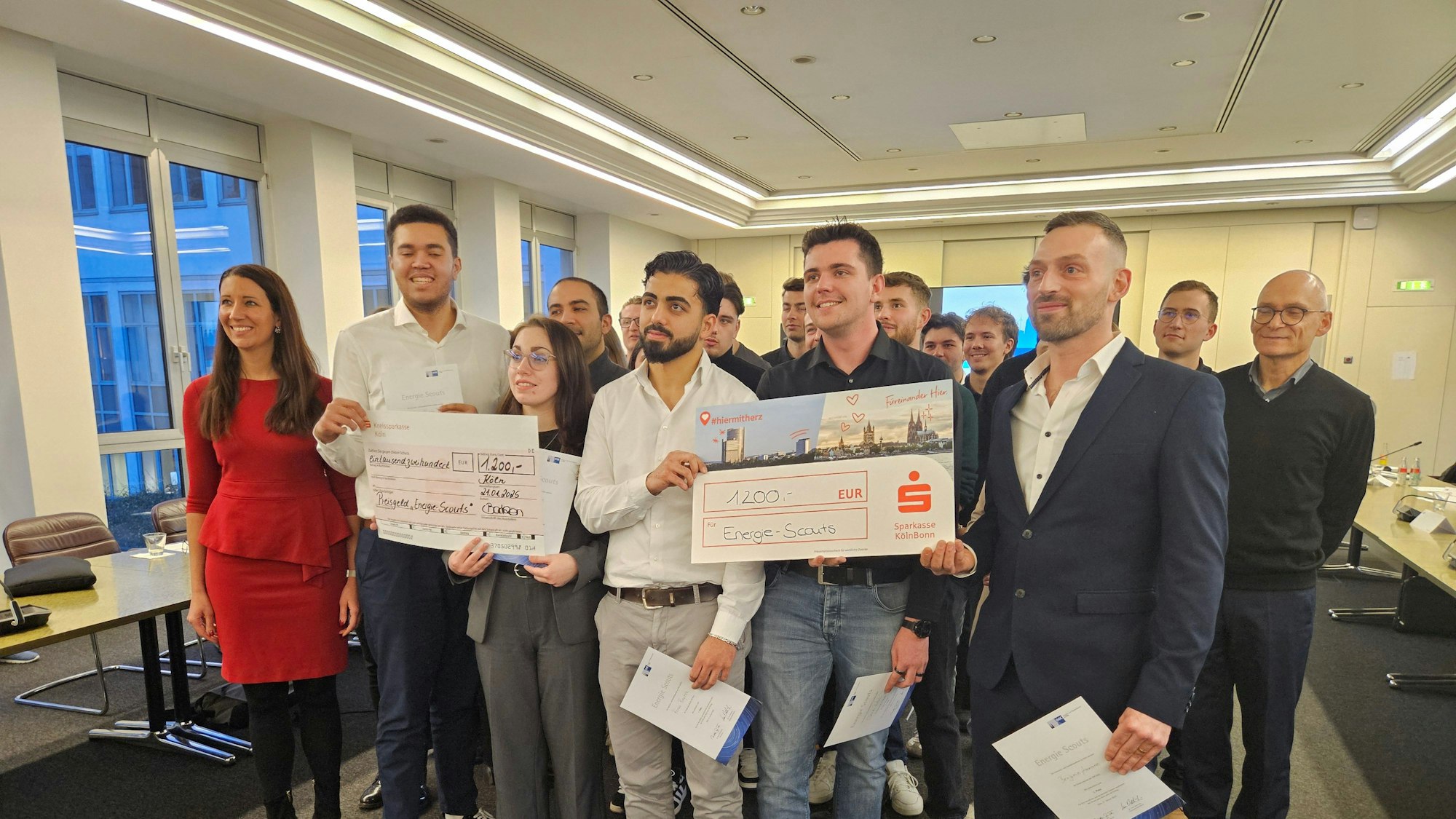 Viele Menschen halten „Preisgeld-Checks“ in den Händen und freuen sich.