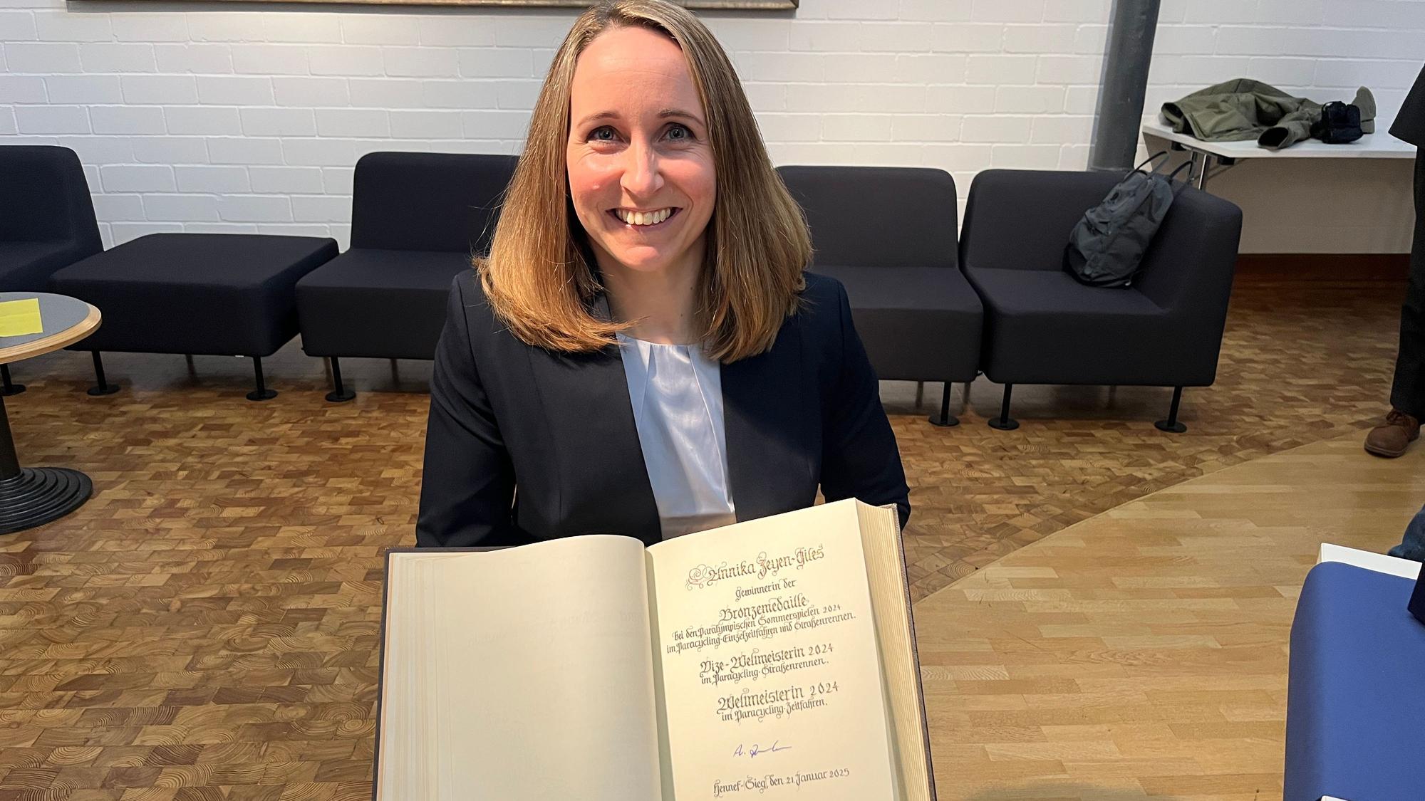 Eine Frau hält das Goldene Buch der Stadt Hennef in Händen.