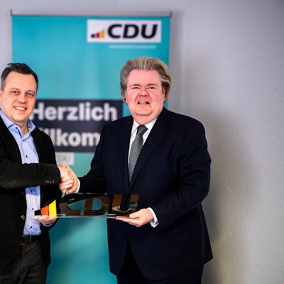 Das Bild zeigt Sacha Reichelt und Klaus Voussem, die die Zusammenarbeit mit einem Handschlag besiegeln