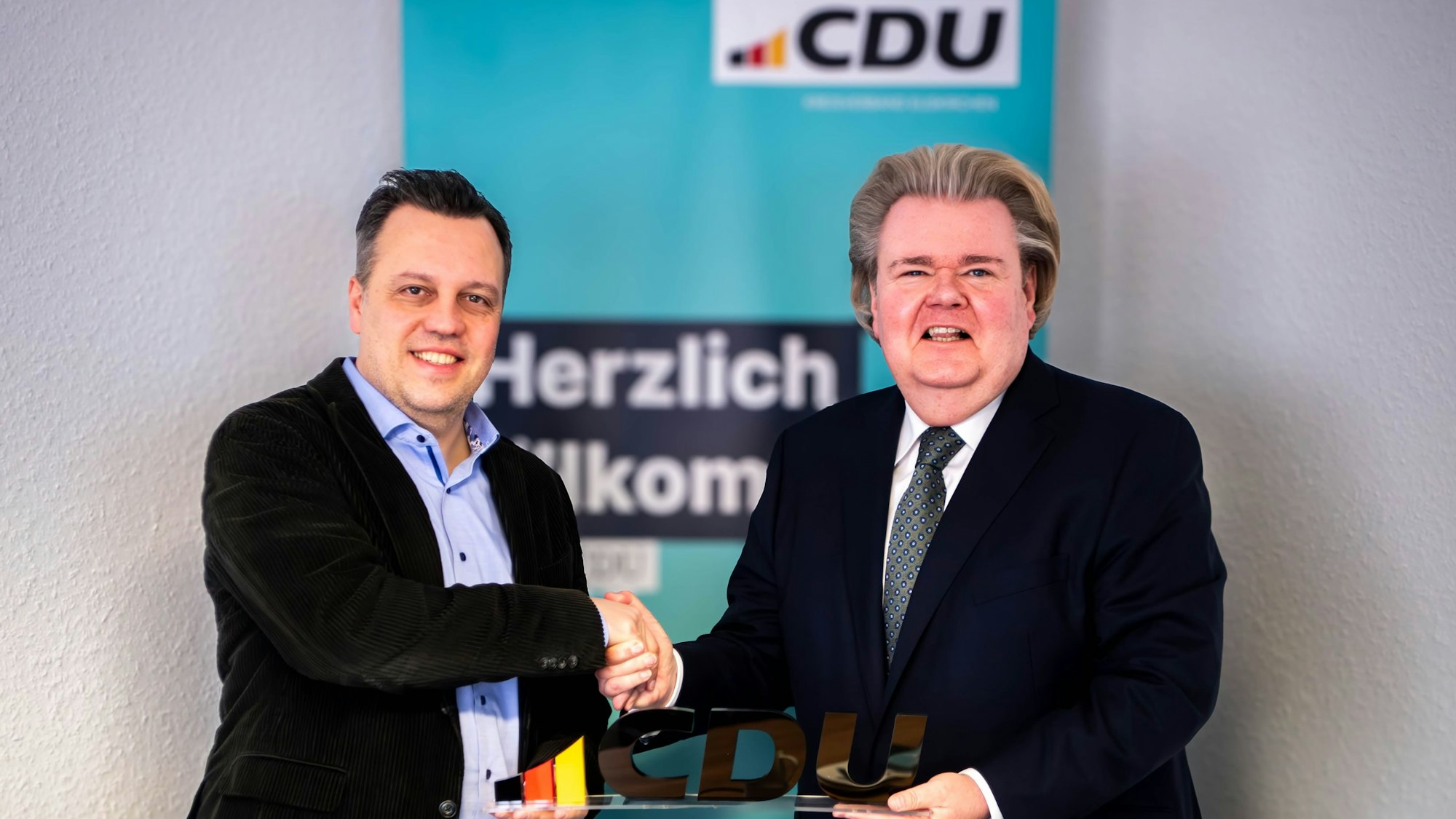 Das Bild zeigt Sacha Reichelt und Klaus Voussem, die die Zusammenarbeit mit einem Handschlag besiegeln