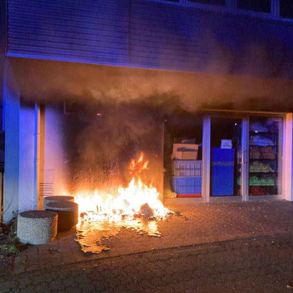 Vor einem Haus brennt eine Mülltonne.