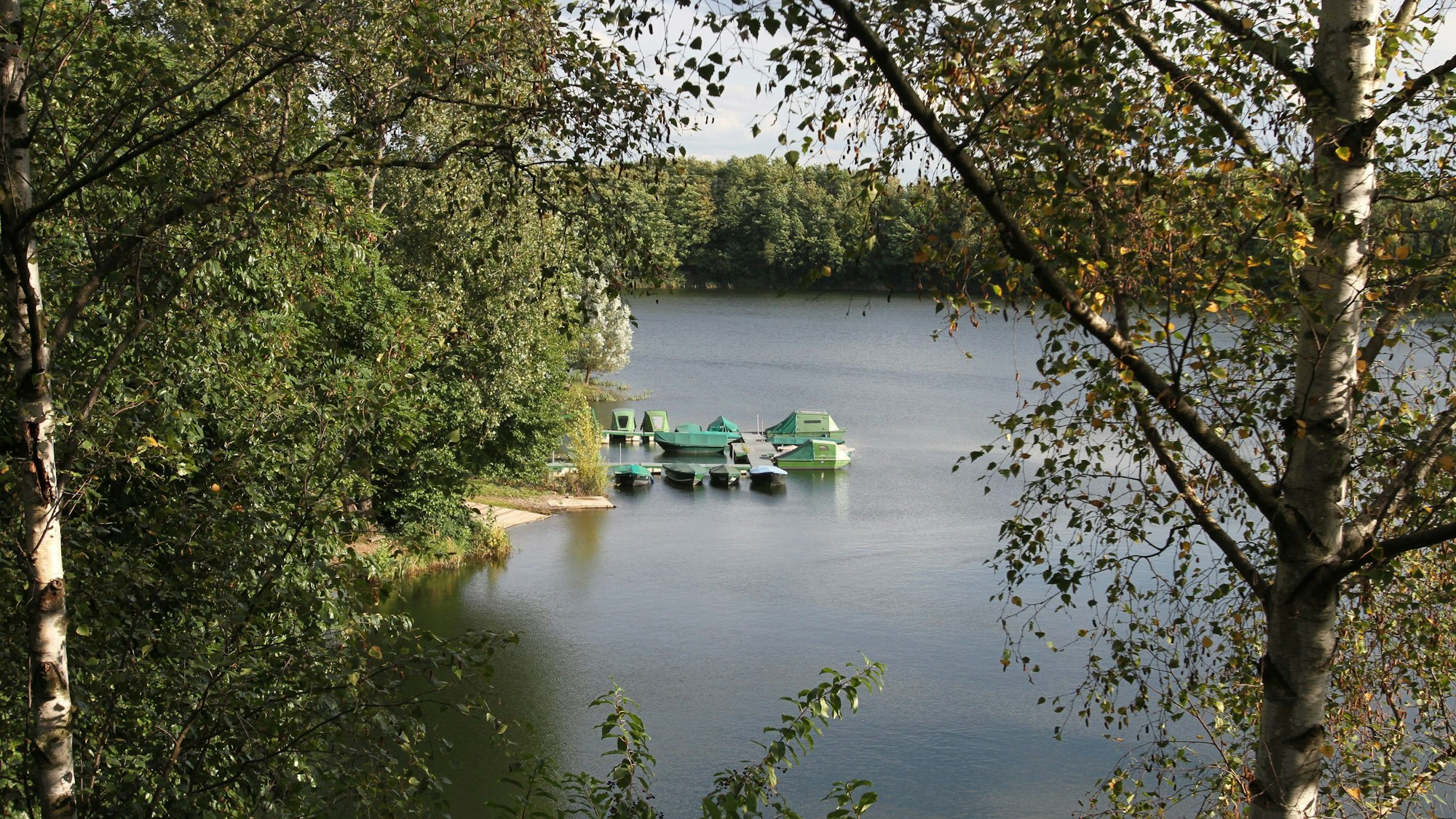 Ein ehemaliger Baggersee mit einem Steg und einzelnen Booten.