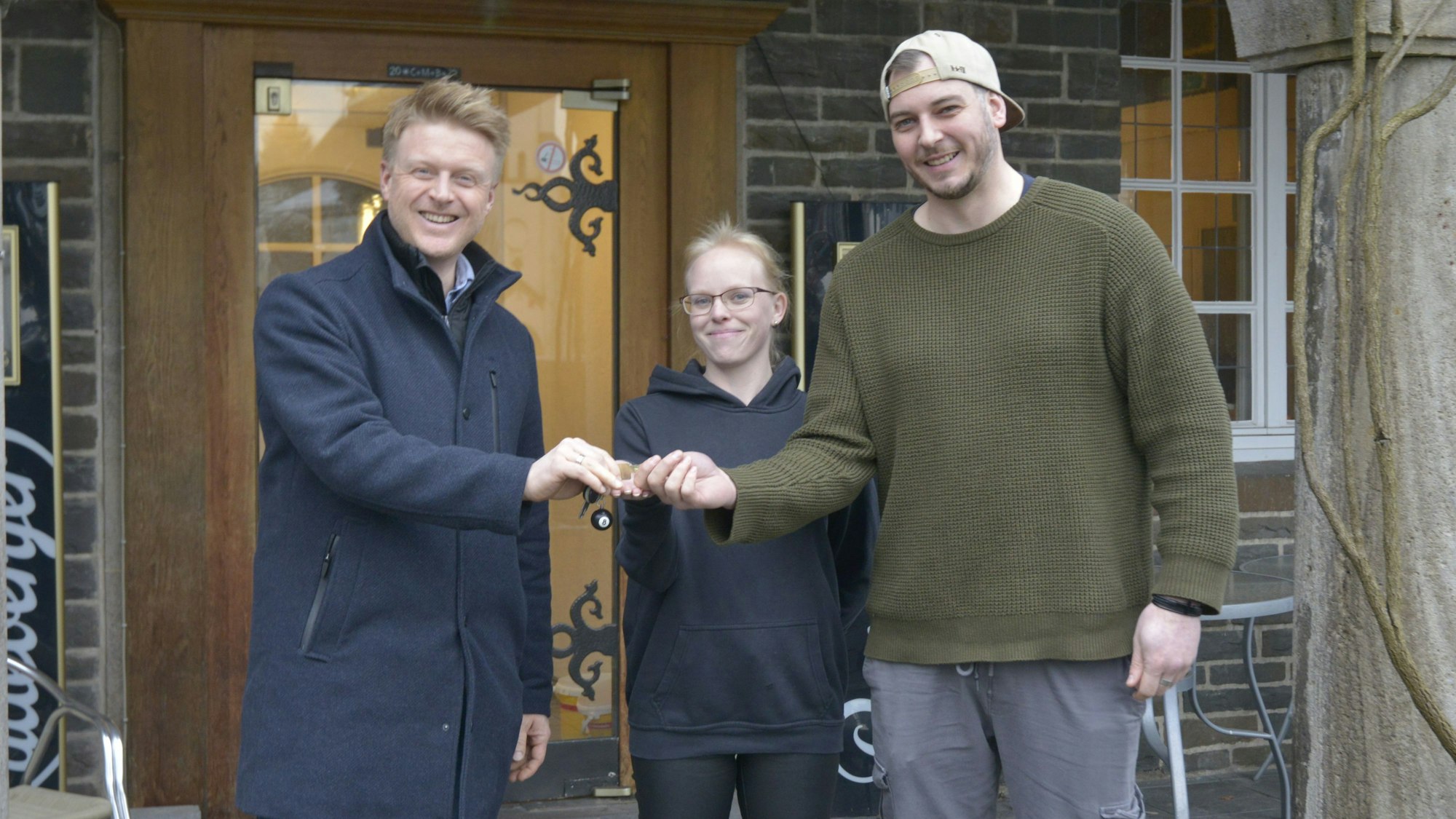 Wipperfürth. City-Manager Lars Schreckegast (l.) übergibt am Mittwoch, 22. Januar, die Schlüssel für das Restaurant Ratskeller symbolisch an Tanja Berghaus und Yannick Mergner.