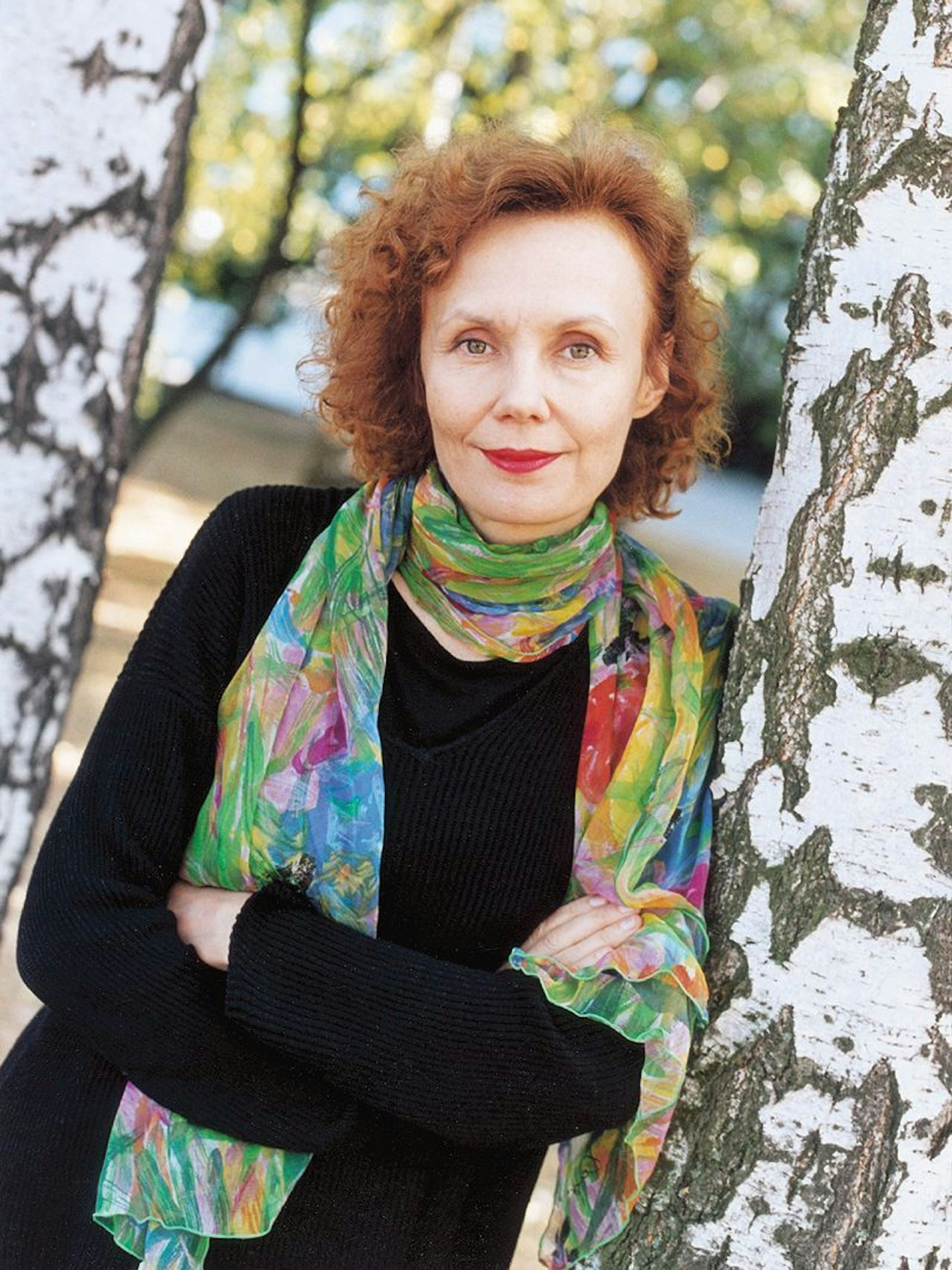 Kaija Saariaho lehnt an einem Baum.