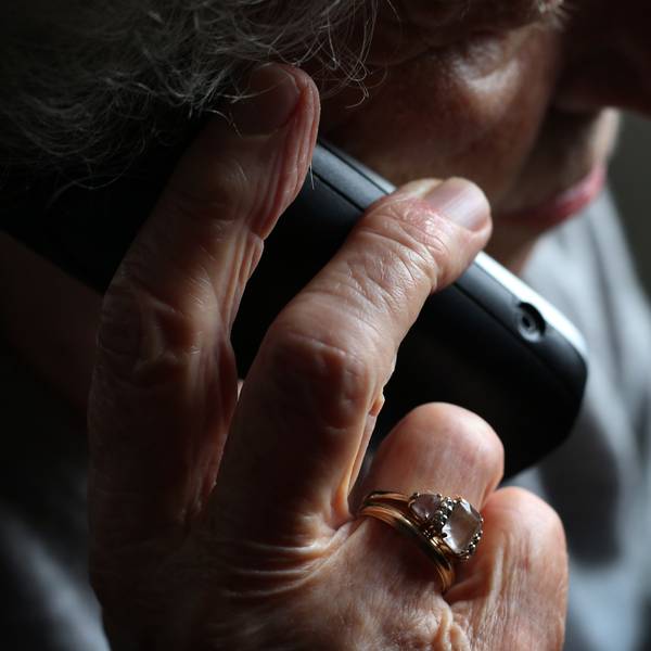 Das Symbolbild (Detailaufnahme) zeigt eine Seniorin, die ein Telefon ans Ohr hält.
