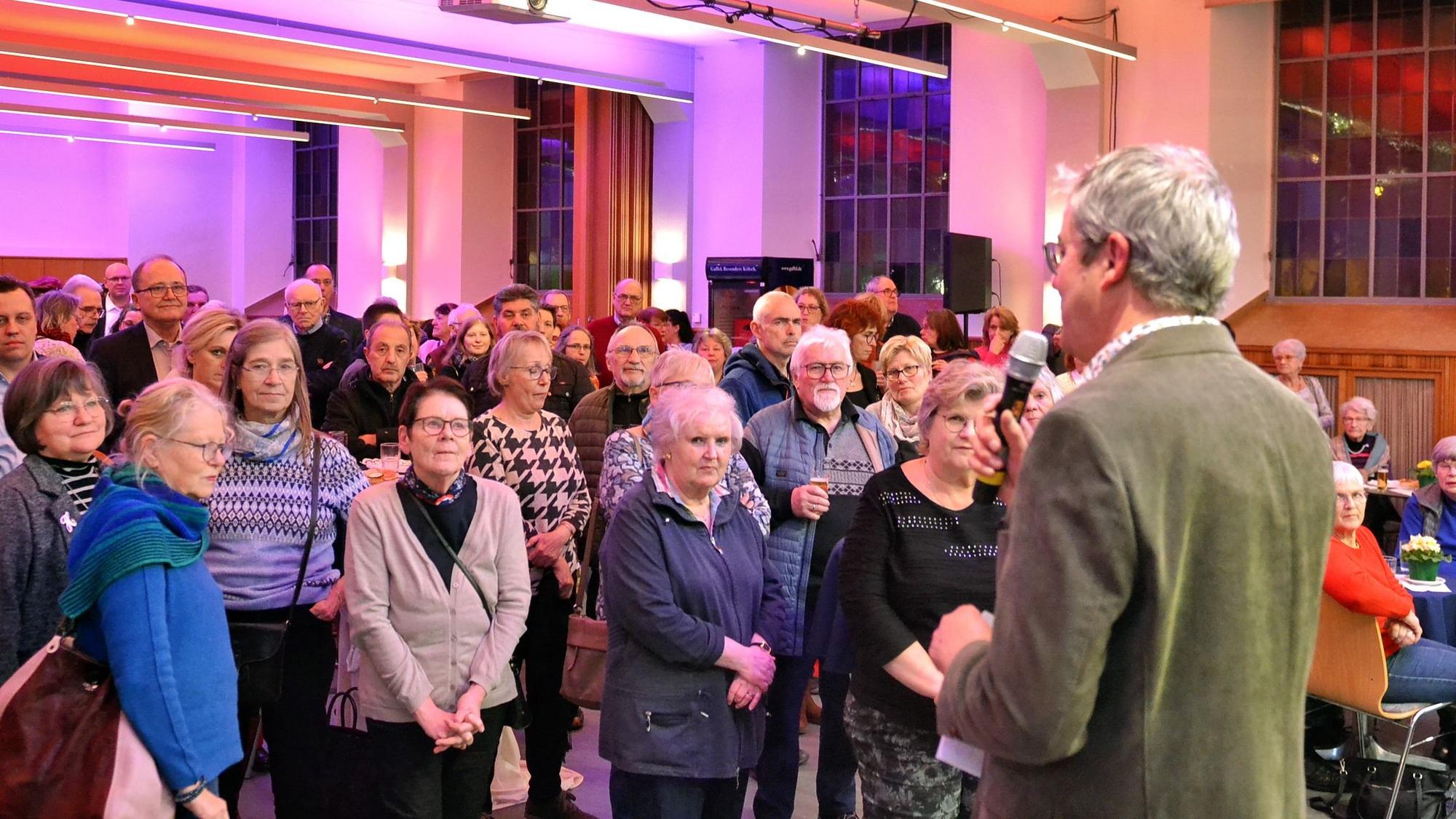 Pfarrer Frank Thönes steht vor einer Gruppe Menschen und spricht in ein Mikrofon.