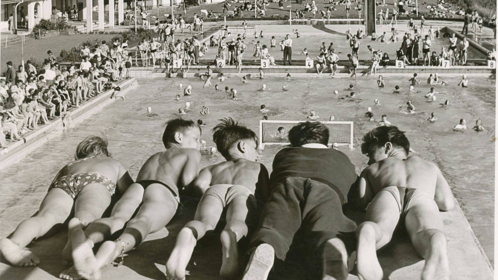 Kinder in Badehosen auf der Plattform eines Sprungturmes-