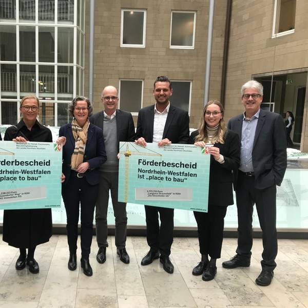 (v. l): Jörn Rickmann und Kathrin Möller von der GAG, Ministerin Ina Scharrenbach, Dezernent Markus Greitemann sowie Martin Bündgens und Sira Müller von der Wohnungsbaugenossenschaft "Die Ehrenfelder"und deren früherer Vorstand Werner Nußbaum