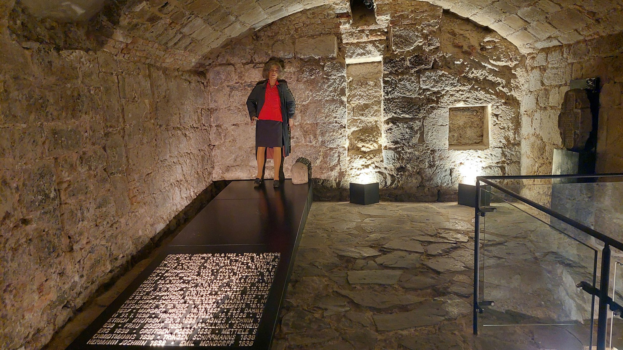 Ein Kellergewölbe, in dem ein Gedenkstein für als Hexen hingerichtete Menschen steht sowie die Figur einer Frau.