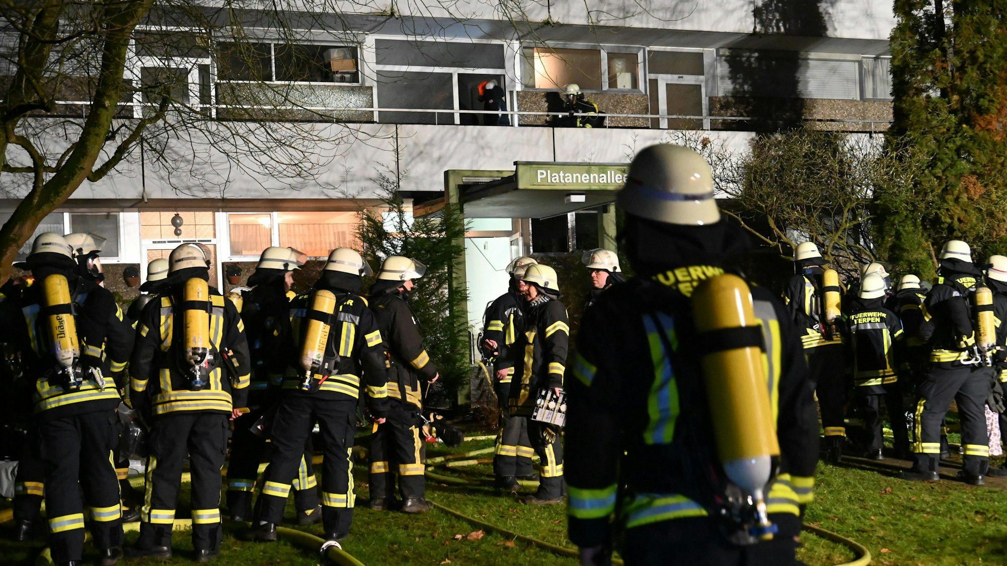 Das Bild zeigt zahlreiche Feuerwehrkräfte vor einem Wohnhaus.