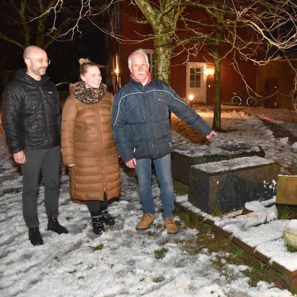 Zu sehen sind zwei Männer und eine Frau vor umgeworfenen Grabsteinen.