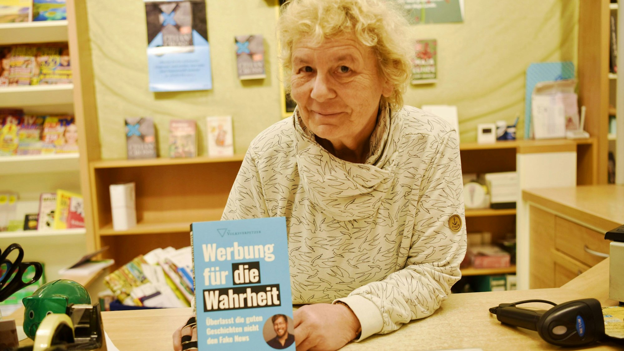 Buchhändlerin Claudia Reinhardt hält das Buch "Werbung für die Wahrheit" von Thomas Laschyk in die Kamera.