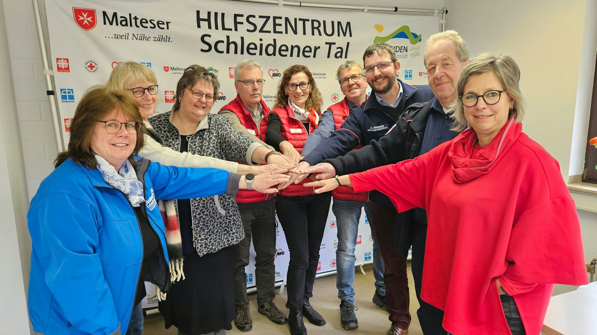 Vertreter der Organisationen stecken die Hände zusammen als Symbol für die gute Zusammenarbeit.