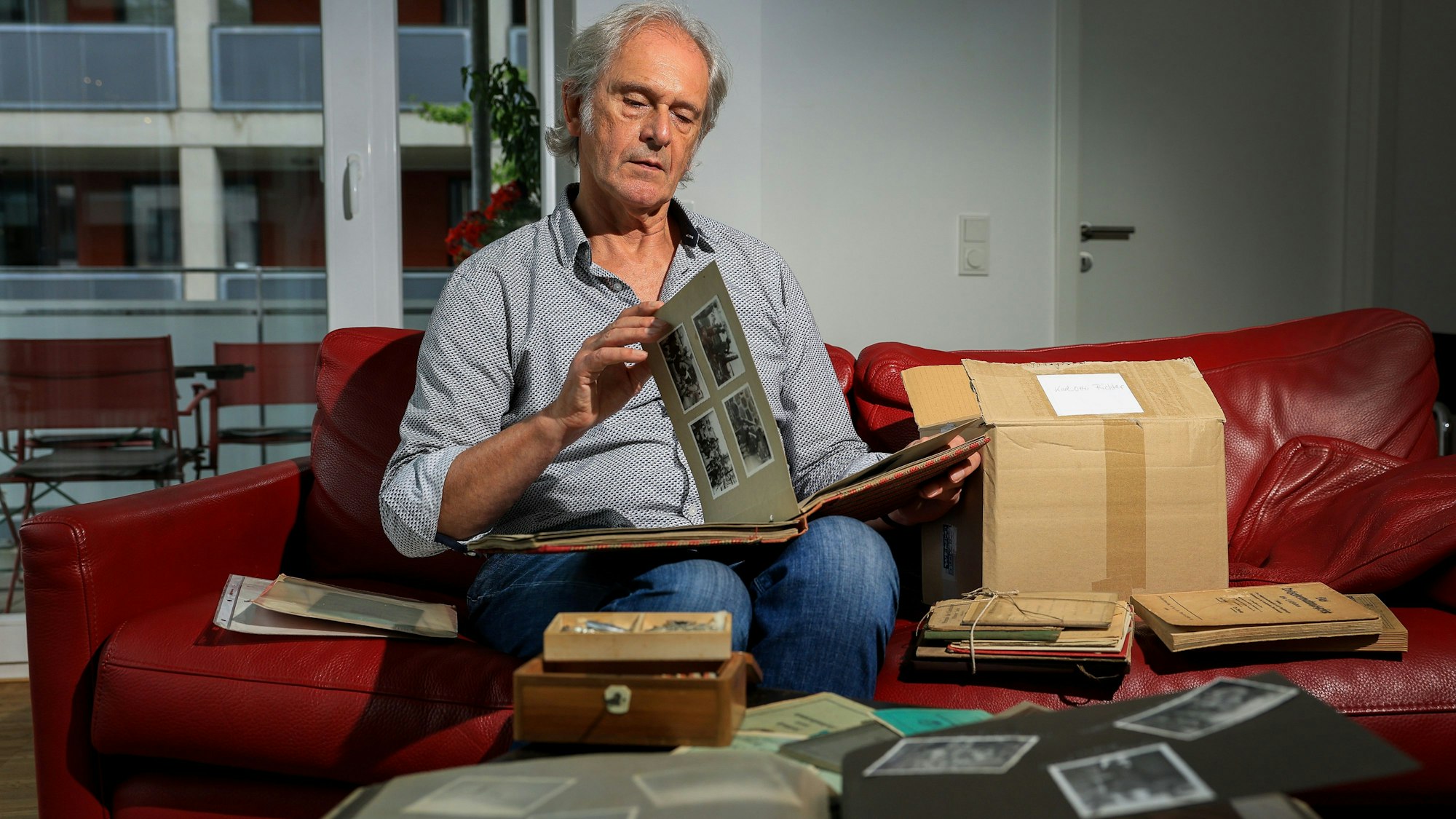 25.09.2024, Köln: Gerhard Richter sitzt auf dem Sofa und blättert Erinnerungsstücke seines Vaters durch.