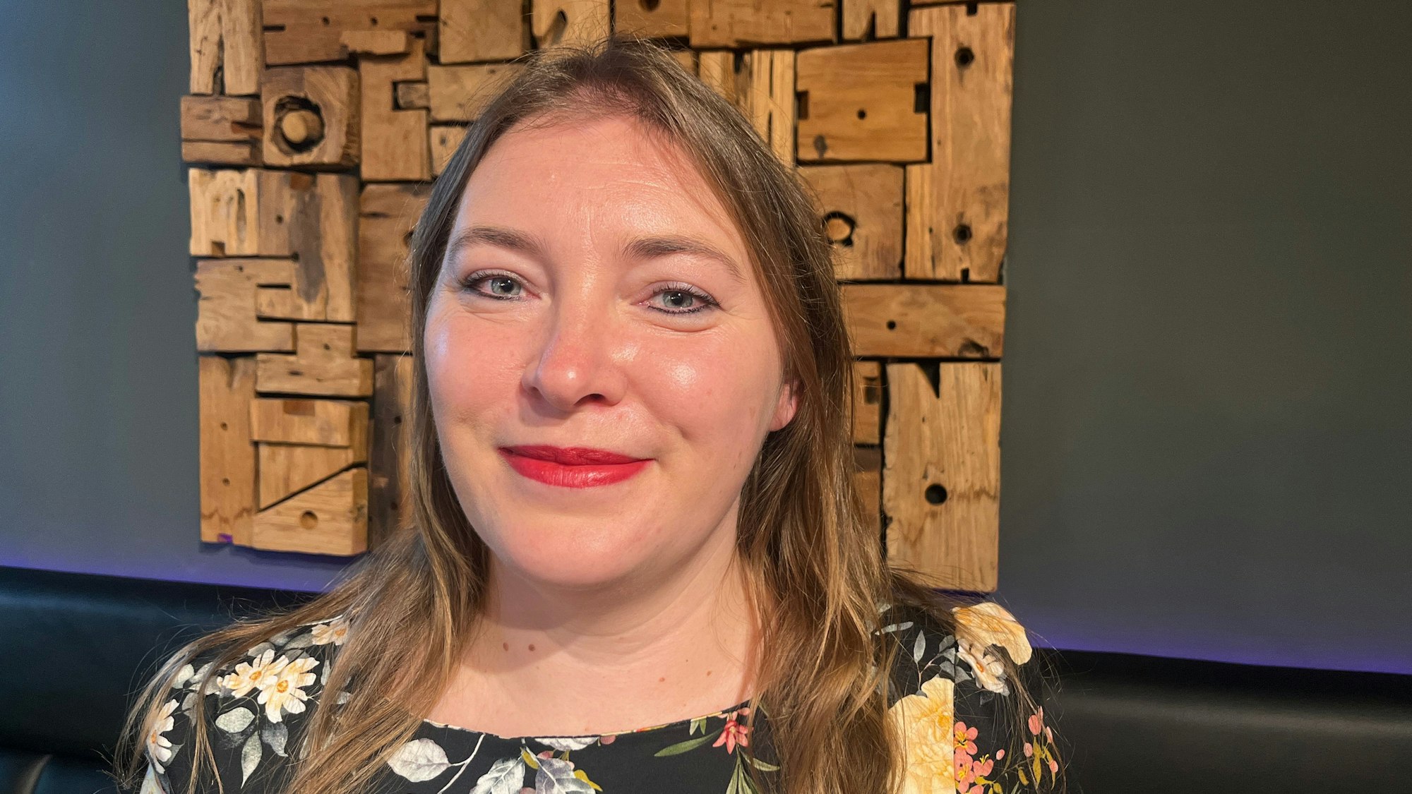 Eine Frau steht vor einem Holzrelief.