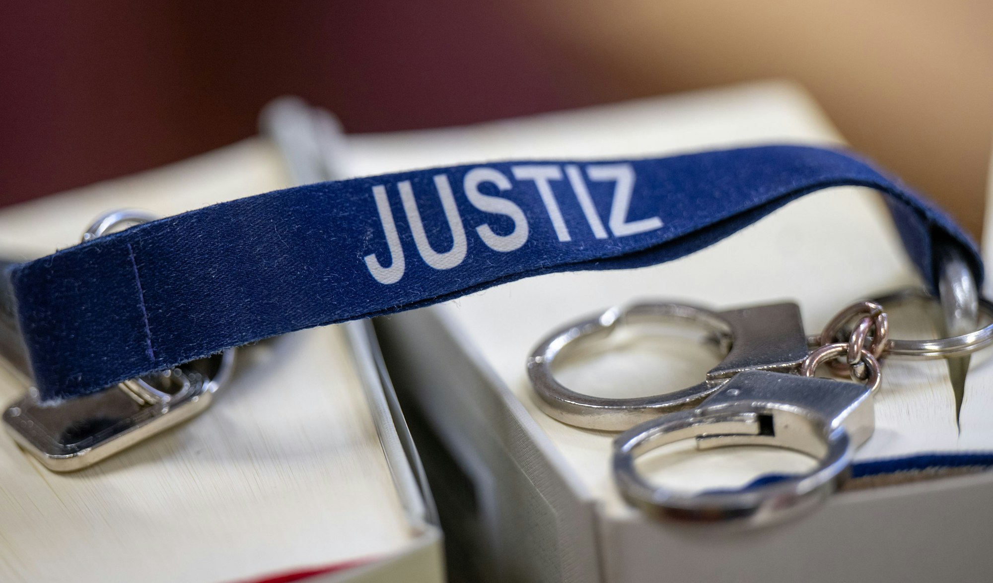 Das Bild zeigt Handschellen und einen Schlüsselanhänger mit dem Aufdruck Justiz
