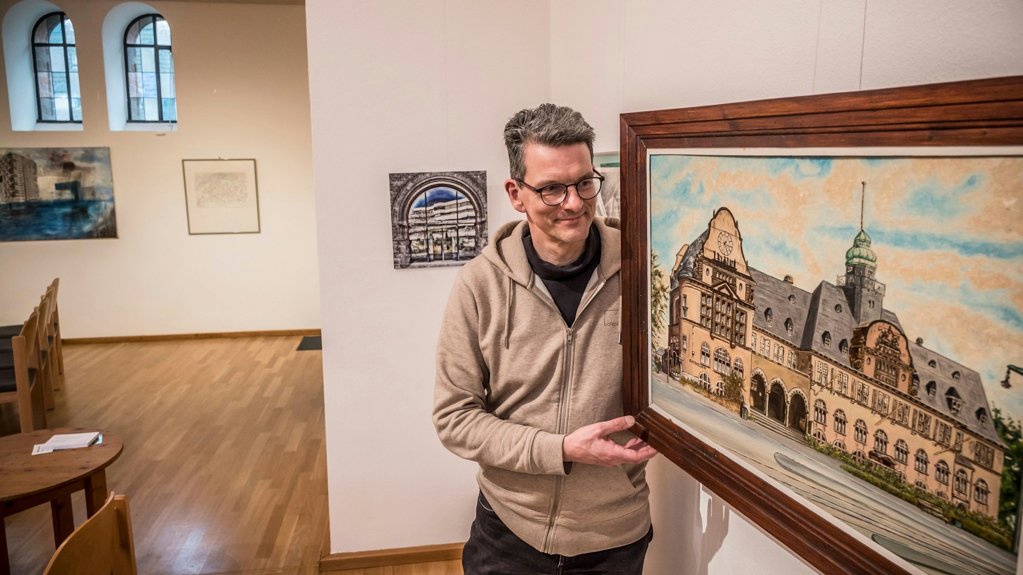 Detlev Prößdorf, Pfarrer an der Christuskirche, hängt Bilder einer Ausstellung mit Lieblingsstücken aus der Gemeinde auf. Foto: Ralf Krieger