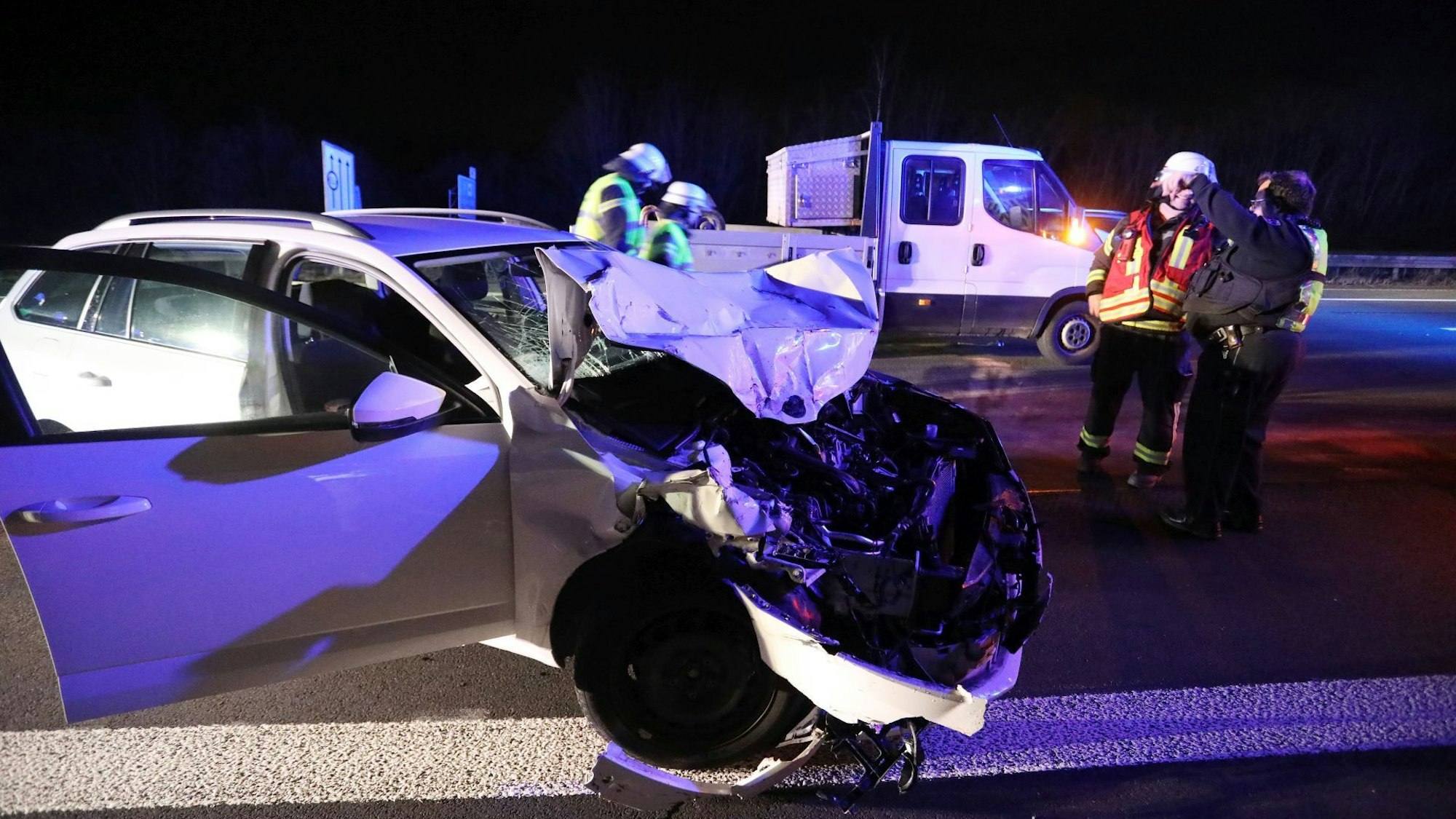Feuerwehrleute stehen neben einem Auto mit demolierter Front