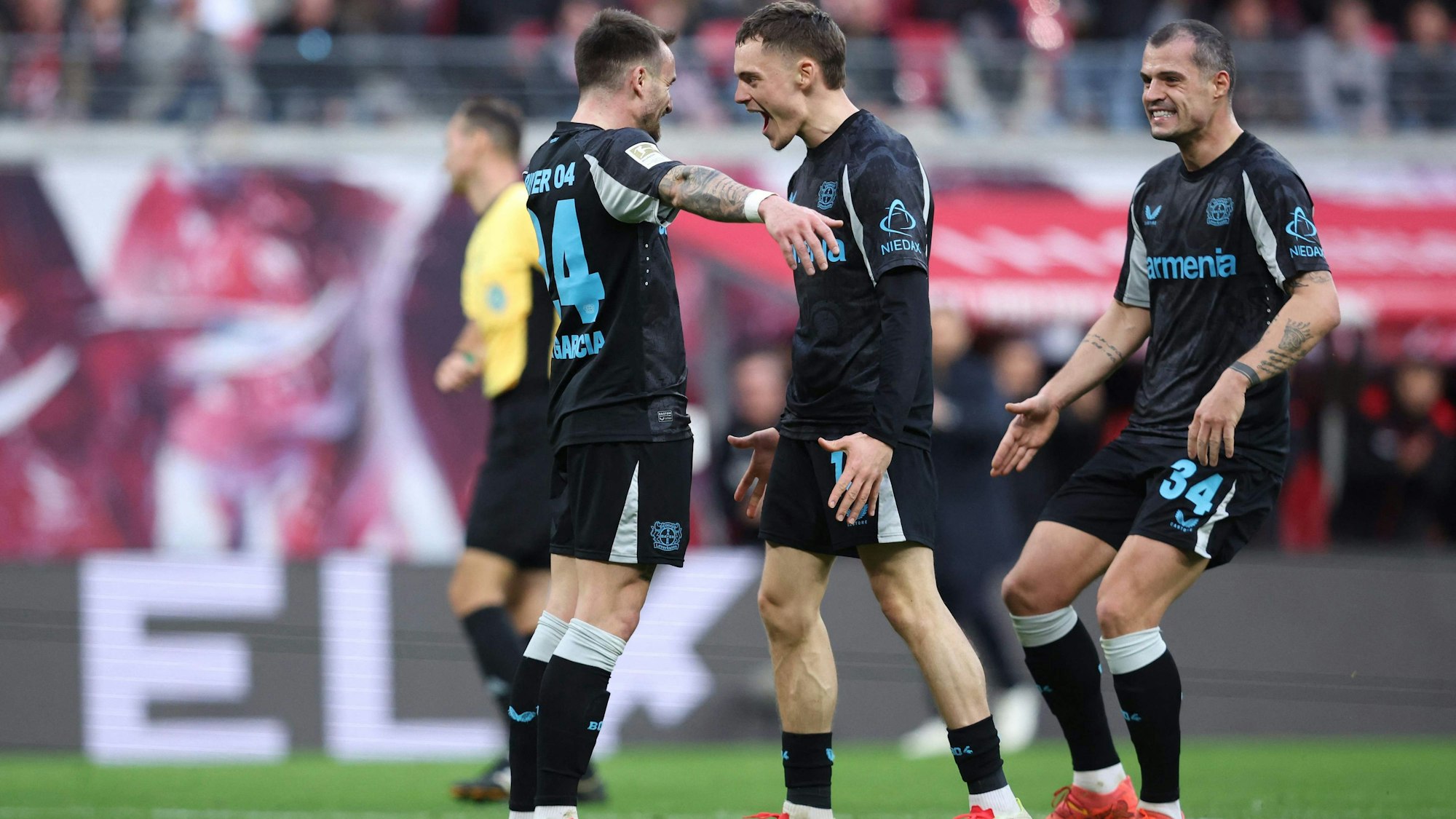 Bayer Leverkusen's Spanish midfielder #24 Aleix Garcia (L) celebrates scoring the 0-2 goal with his teammates Bayer Leverkusen's German midfielder #10 Florian Wirtz and Bayer Leverkusen's Swiss midfielder #34 Granit Xhaka during the German first division Bundesliga football match RB Leipzig vs Bayer 04 Leverkusen in Leipzig, eastern Germany on January 25, 2025. (Photo by Ronny HARTMANN / AFP) / DFL REGULATIONS PROHIBIT ANY USE OF PHOTOGRAPHS AS IMAGE SEQUENCES AND/OR QUASI-VIDEO