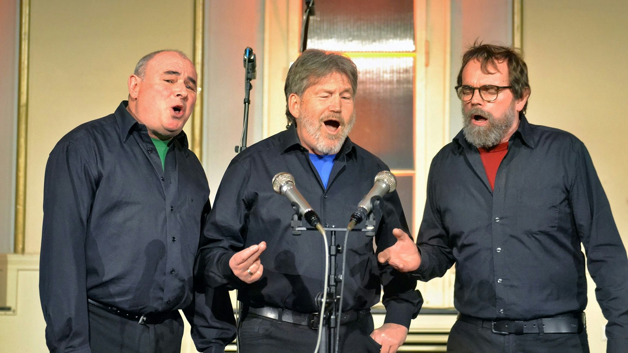 Bruno Schreiner, Robert Kunze und Robert Schloeßer stehen vor Mikrofonen und singen.