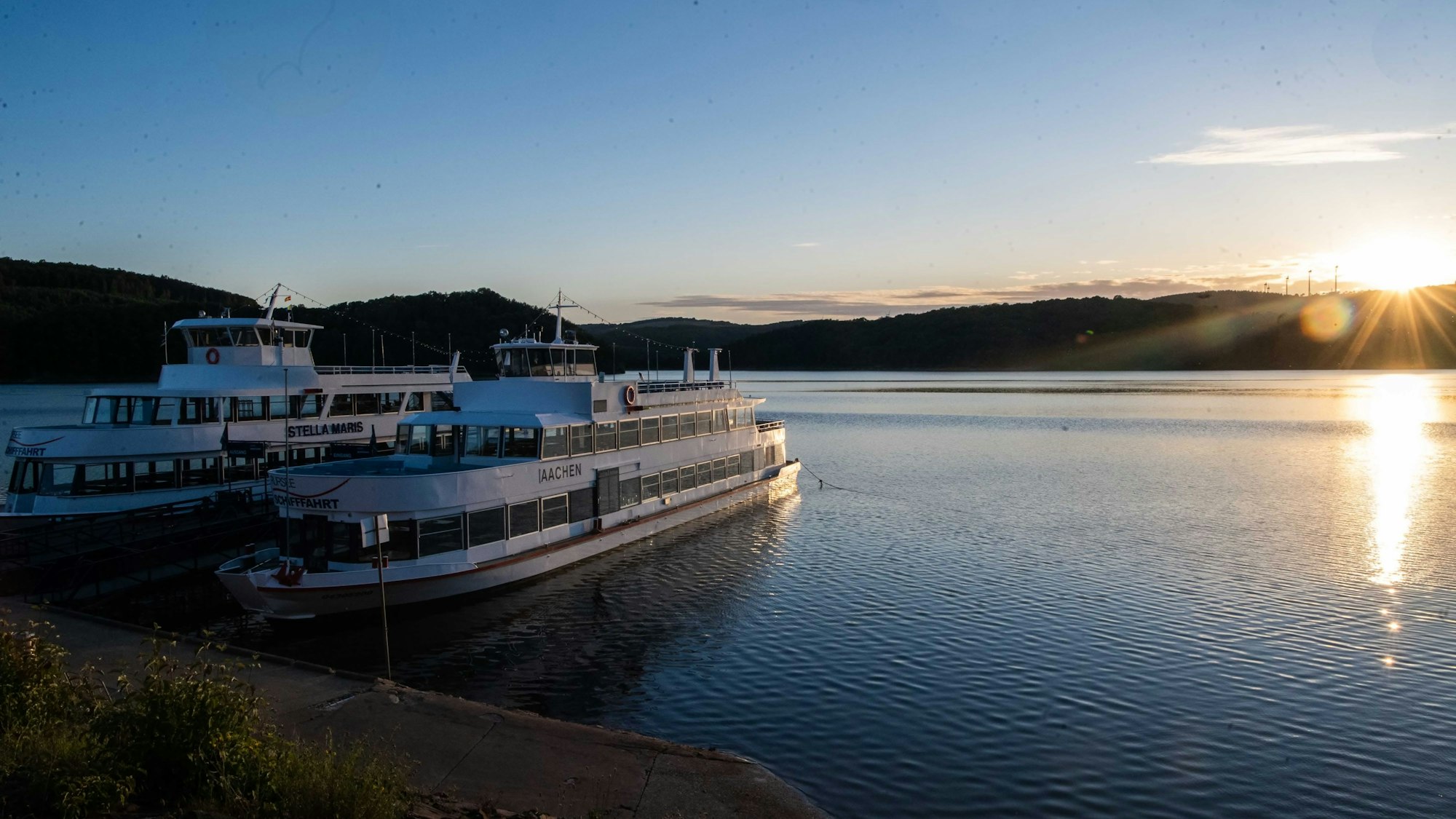 Das Bild zeigt einen Blick auf den Rursee, links liegen zwei Ausflugsschiffe im Wasser.