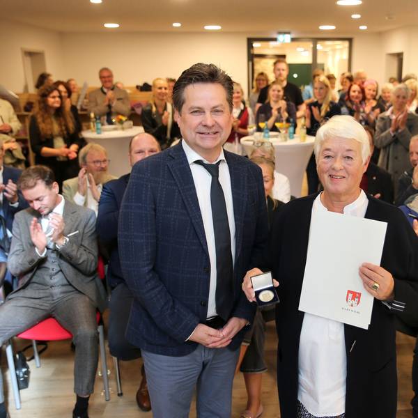 Ein Mann und eine Frau vor einer applaudierenden Menge.