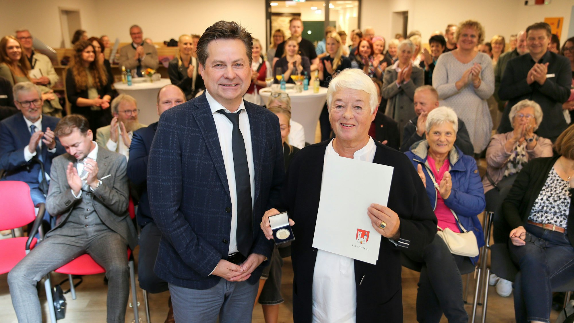 Ein Mann und eine Frau vor einer applaudierenden Menge.