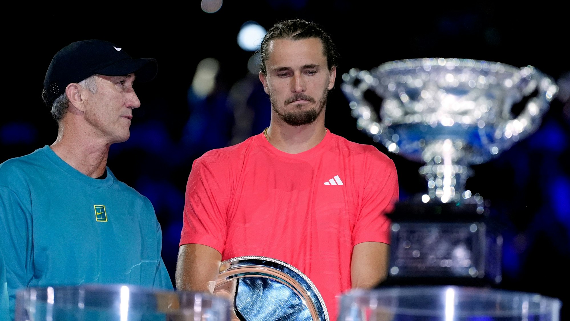Alexander Zverev steht nach seiner Niederlage enttäuscht hinter dem Norman Brookes Challenge Cup und neben Darren Cahill (l.), dem Trainer von Sinner.