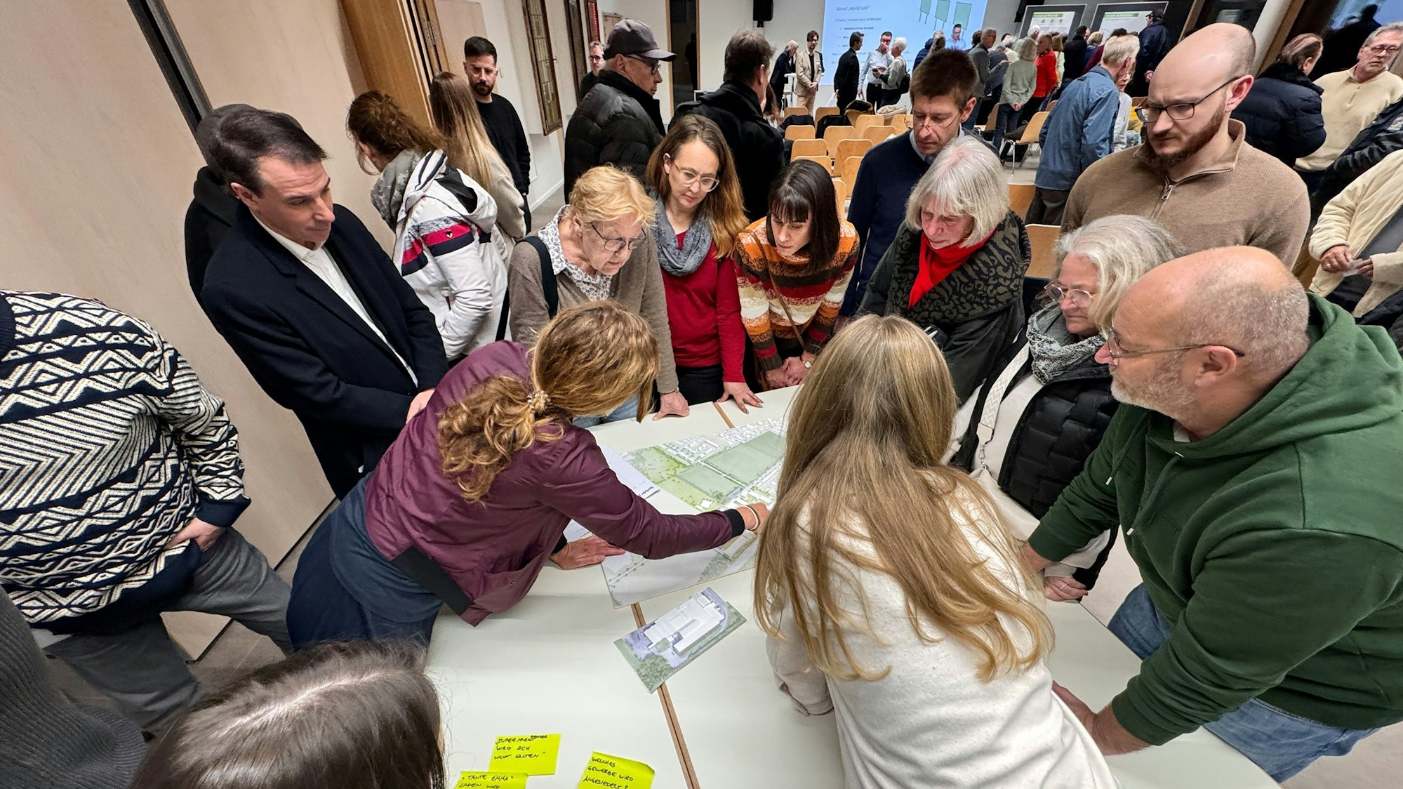 Zu sehen sind zahlreiche Bürgerinnen und Bürger, die sich über einen Plan beugen.