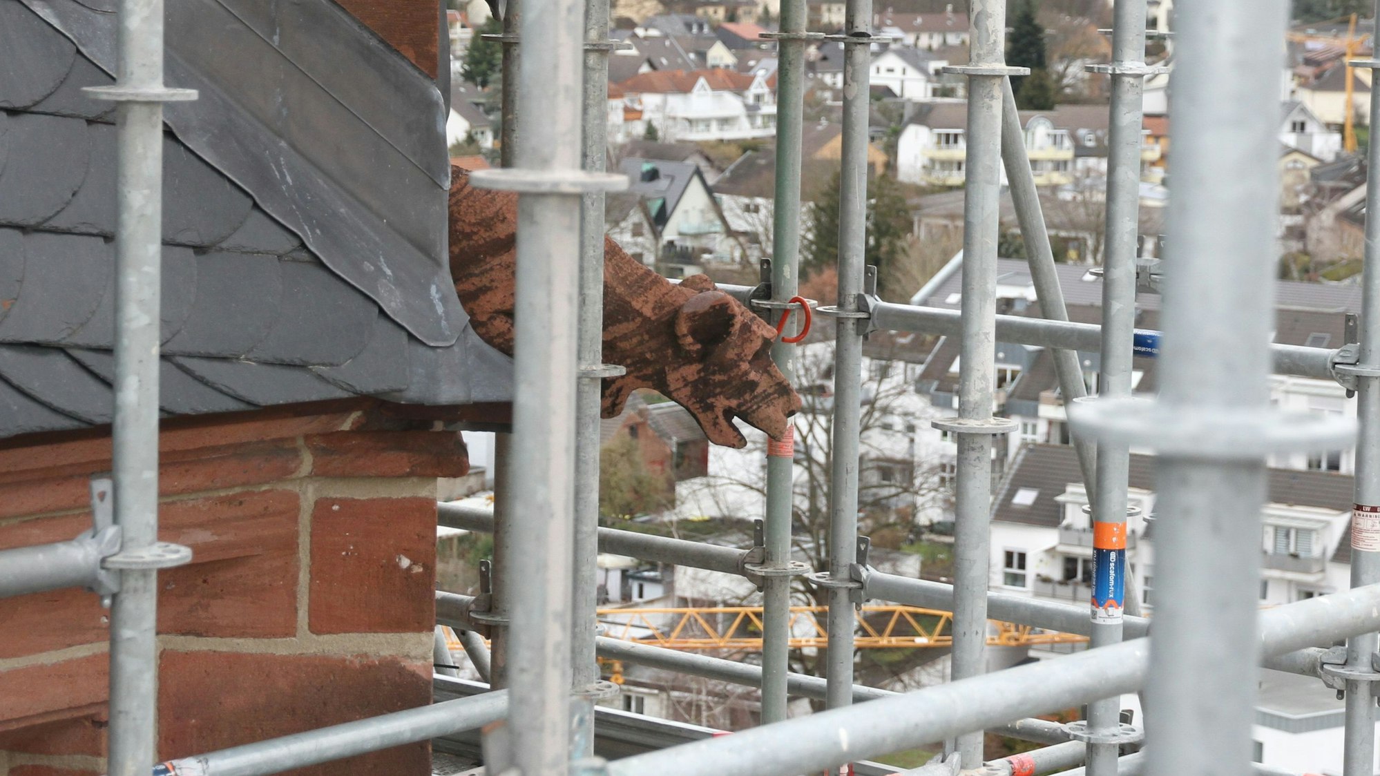 Ein Gerüst und ein Wasserspeier an einem Kirchturm.